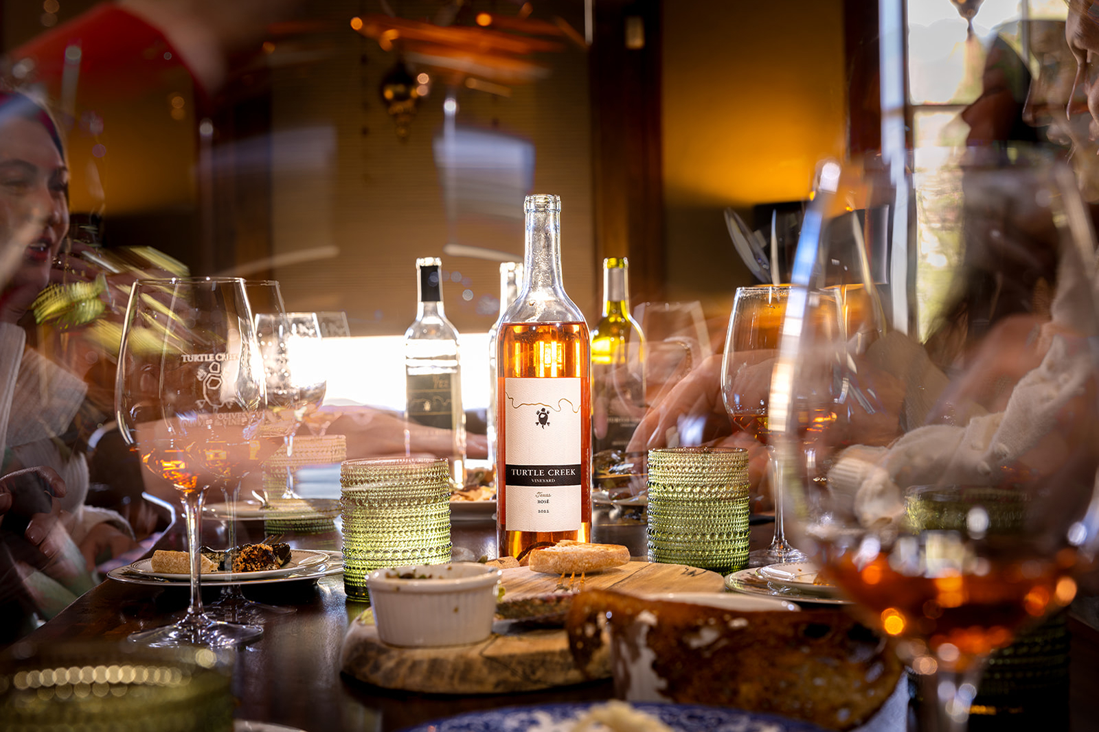 Turtle Creek Vineyard rosé bottle on tasting room table surrounded by wine glasses, appetizers, and guests during winery experience